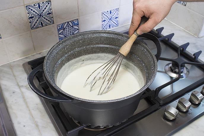 Preparate adesso la besciamella. Fate fondere il burro in una pentola a fondo spesso, aggiungete la farina e cuocetela fino a farla virare leggermente al colore nocciola. Aggiungete adesso a filo tutto il latte previsto nella ricetta. Via via che aggiungete il latte, incorporatelo al composto di burro e farina cercando di eliminare con una spatola o una frusta ogni eventuale grumo; all'inizio quindi versate il latte molto gradatamente! Versato tutto il latte, aggiustate con un pizzico di sale, condite con pepe e noce moscata a piacere e cuocete la besciamella fino a farla addensare mescolando in continuazione. Vi consiglio per questa ricetta una besciamella non troppo "densa" e non eccessivamente salata, poichè il salmone e il grana insaporiranno ulteriormente la preparazione.